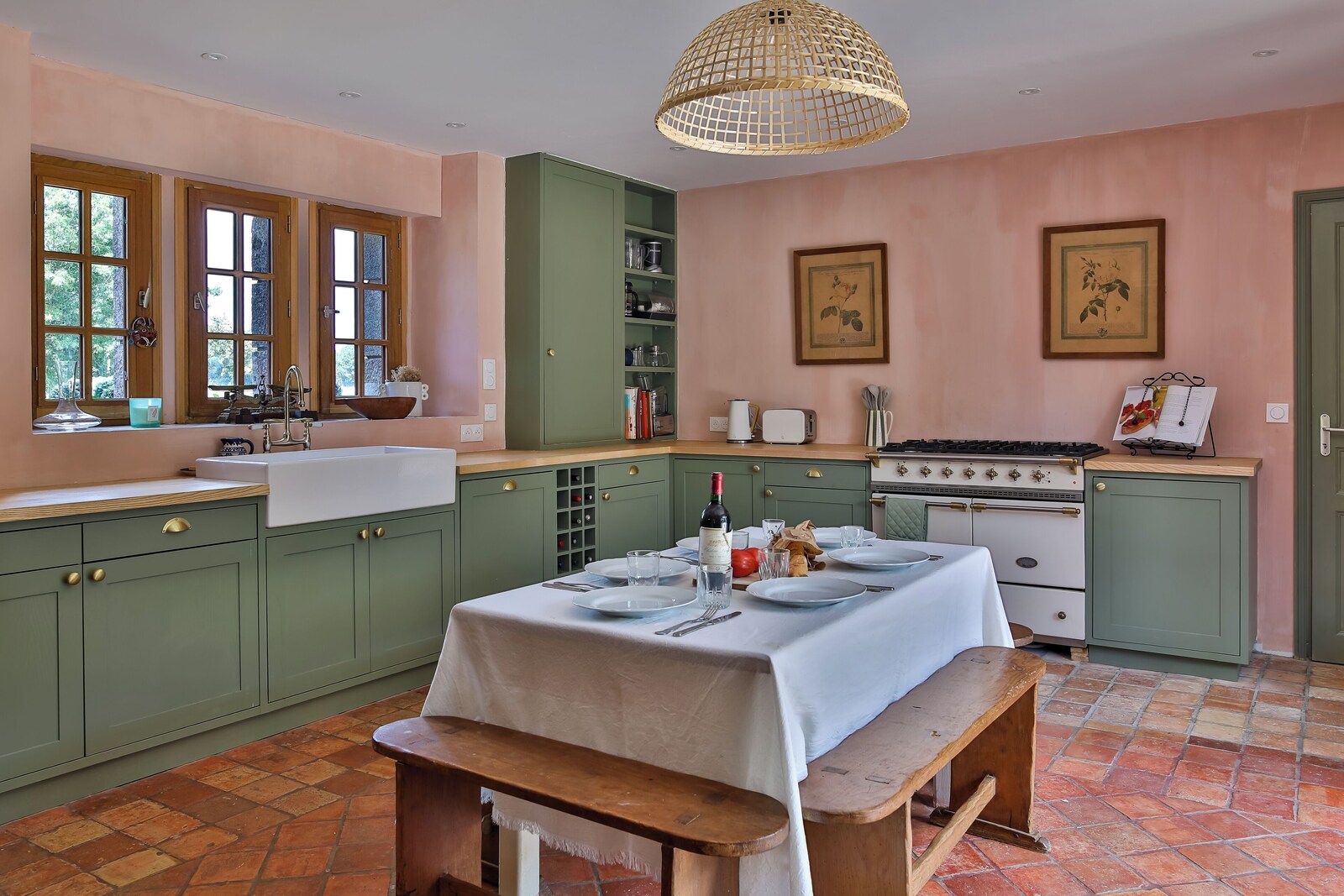 Le Cholo's country kitchen with sage cabinetry, pink walls and a Lacanche range